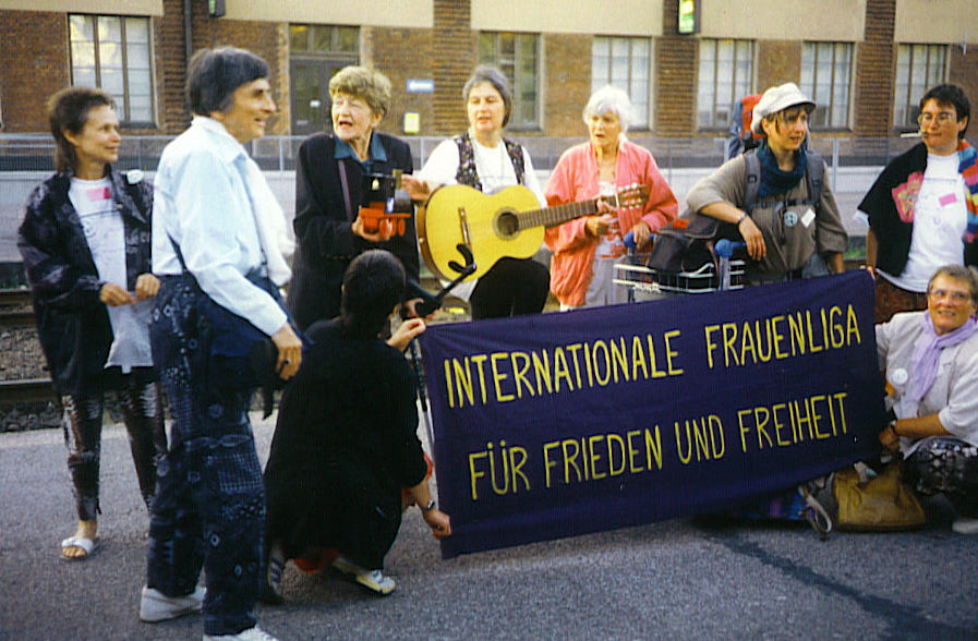 Stock photo from 1995. Women behind a WILPF banner on a train station. One with a guitar.